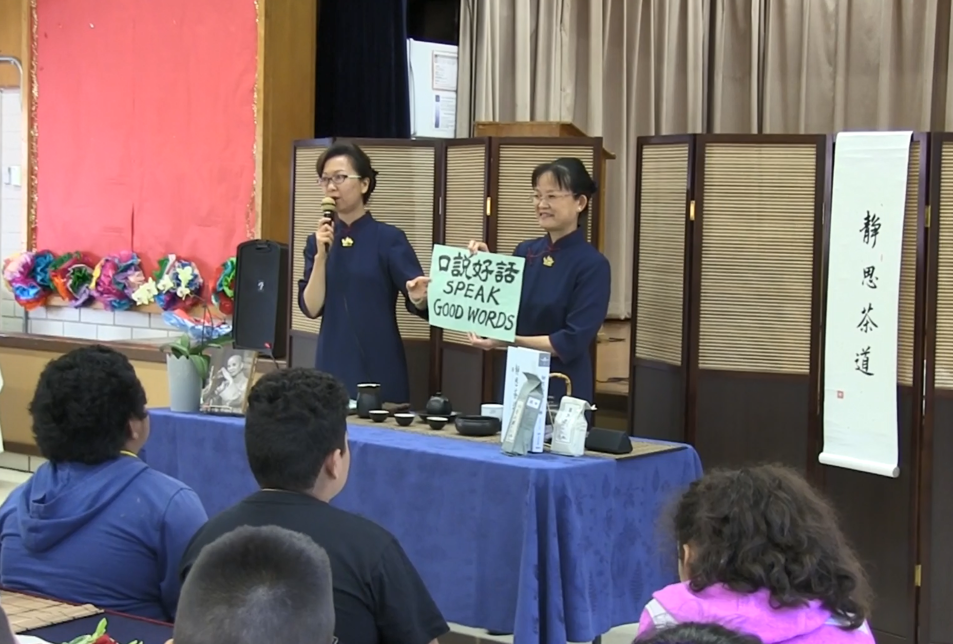 志工黃芳文（左）向學生說明，我們喝的是與眾不同的「三好茶」，每喝一次都對自己分別發願要「心發好願、口說好話、身行好事。」