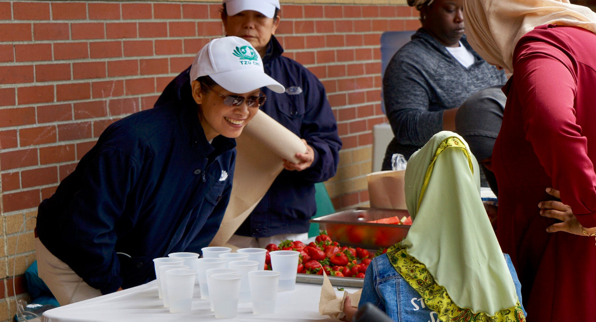 志工陳瓊瑤（左一）親切的招呼小朋友拿準備好的草莓及西瓜。攝影／石秀鳳