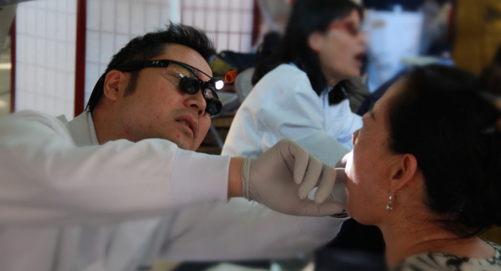 江捷豪醫生（左）細心的為民眾檢查口腔與牙齒並提供建議。攝影／張立甲