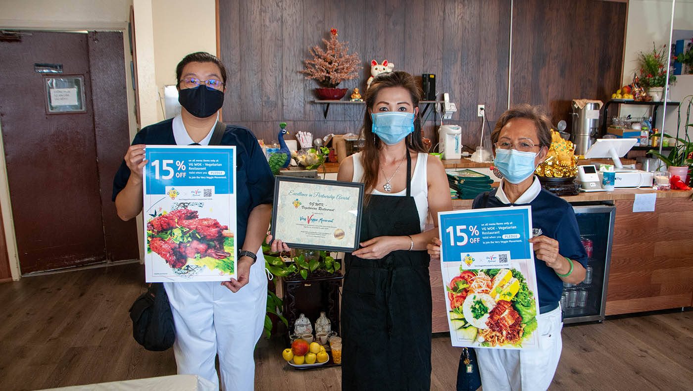 VG Wok’s owner, Tammy Pham, happily takes photos with the beautiful posters and a certificate of appreciation. Photo by Roger Lin.