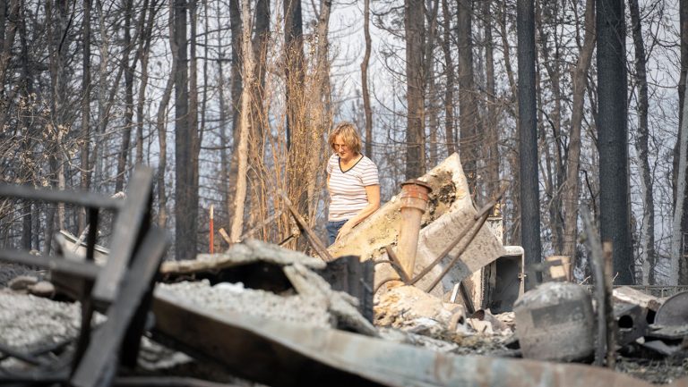 罗嫔·古德温（Robyn Goodwin）走到废墟家园中，搜索未被大火烧成灰烬的物品。摄影 / 曾奂珣