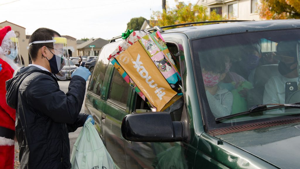 一輛小廂型車上坐滿了一家三代老小，收到滿滿好幾袋的禮物物資後，全家人一起向車窗外的所有慈濟志工們大喊：「聖誕快樂。」攝影／朱文廣