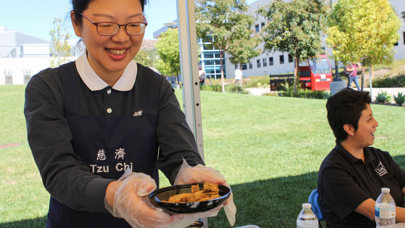 A Tzu Chi volunteer offers Jing Si multi-grain biscuits for students to taste. Photo by Michael Tseng.