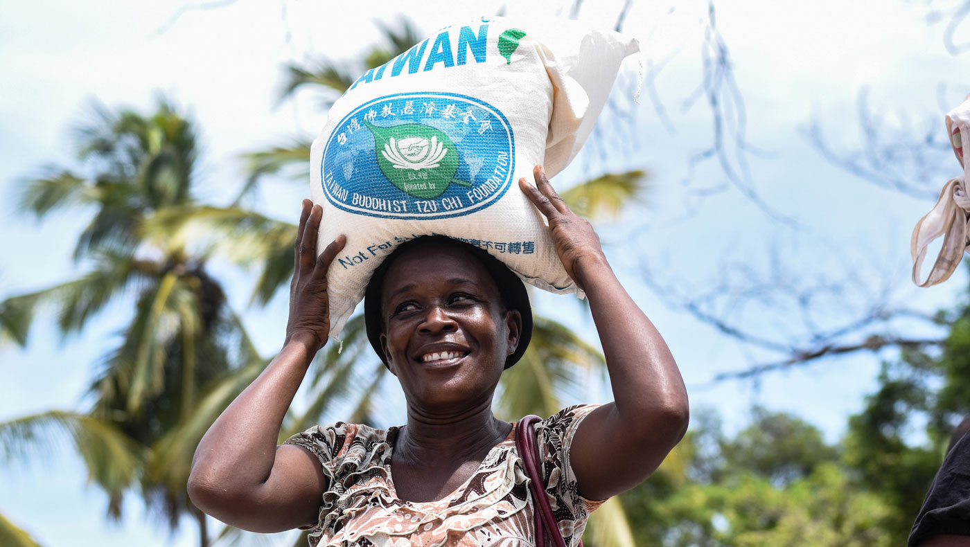 La madre Guerda Goger,  lleva en la cabeza la bolsa de arroz que recibió cuando sale de la distribución. Foto Keziah Jean.