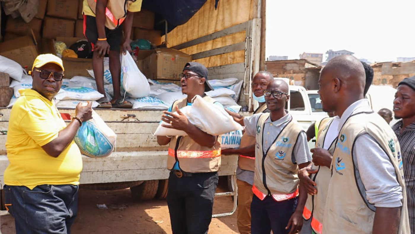 Members of Caritas Freetown and the Healey International Relief Foundation unload trucks carrying bags of rice. Photo/Desmond Jones and Mohamed Dakowa