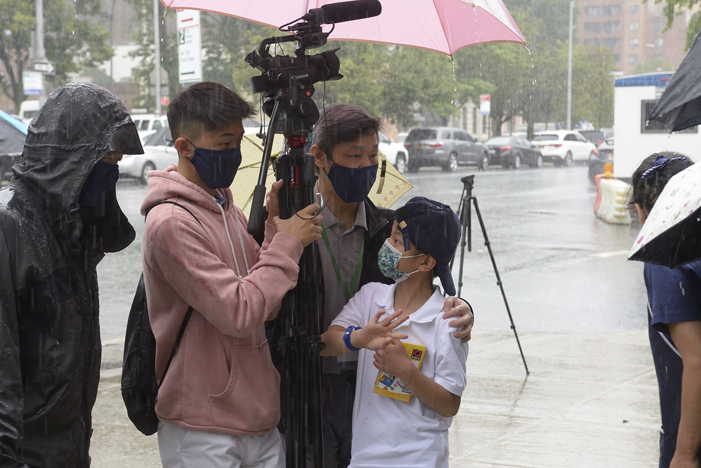人文真善美志工邱志遠與慈少Terry，在開幕過程降下傾盆大雨時，父子倆一人拍攝一人打傘，仍繼續錄影捕捉重要畫面。攝影／朱澤人