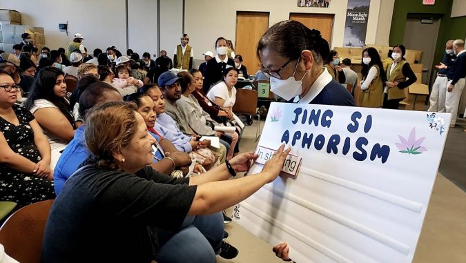 Tzu Chi volunteers keep care recipients in the waiting area entertained with an activity introducing Dharma Master Cheng Yen’s Jing Si Aphorisms