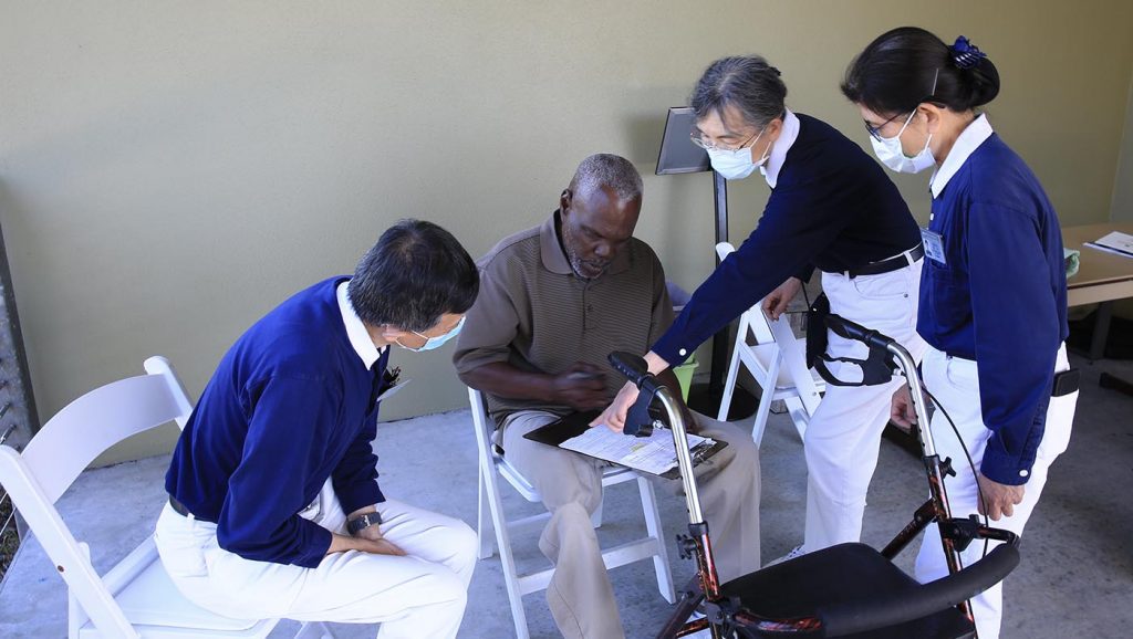 Tzu Chi volunteers attentively assist Kenneth Williams who has limited mobility.