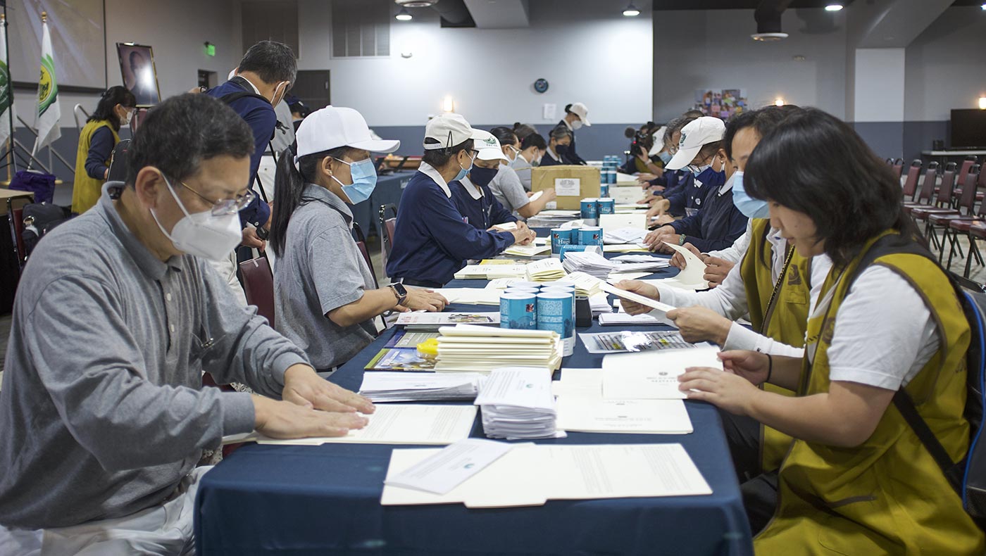 Volunteers carefully pack cash cards alongside letters from Tzu Chi’s founder, Dharma Master Cheng Yen. Photo/Qihua Luo