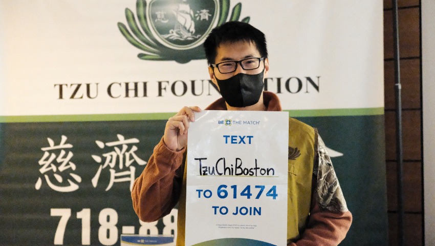 Tzu Chi volunteer David Jiang holding bone marrow donation promotion poster