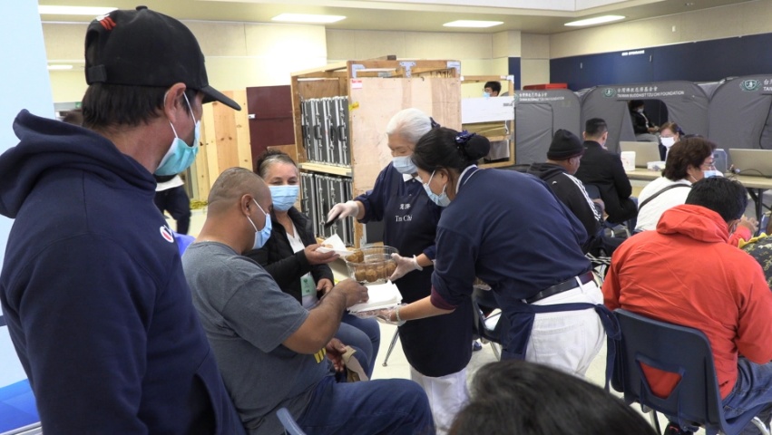 Tzu Chi volunteers offering vegetarian snacks to recipients