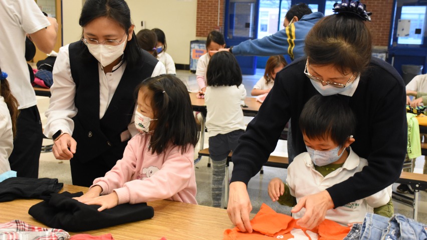 志工們為低年級同學悉心講解折疊衣物的方法。