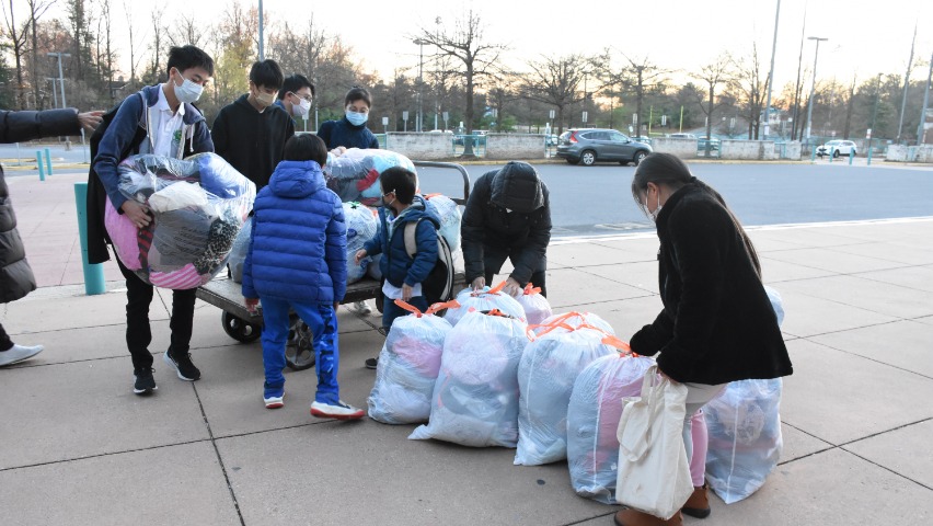 打包完成後，由高年級學生利用平板拖車協助把衣物運送至校門口，上車載走。
