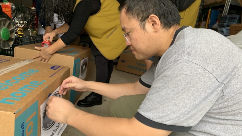 志工陳聖閎用心地在箱子上貼上慈濟標誌的貼紙。攝影／黄詠詩