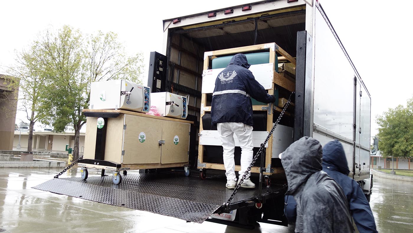 志工在大雨中將義診所需的器具從大貨車中卸下。攝影／顏國興