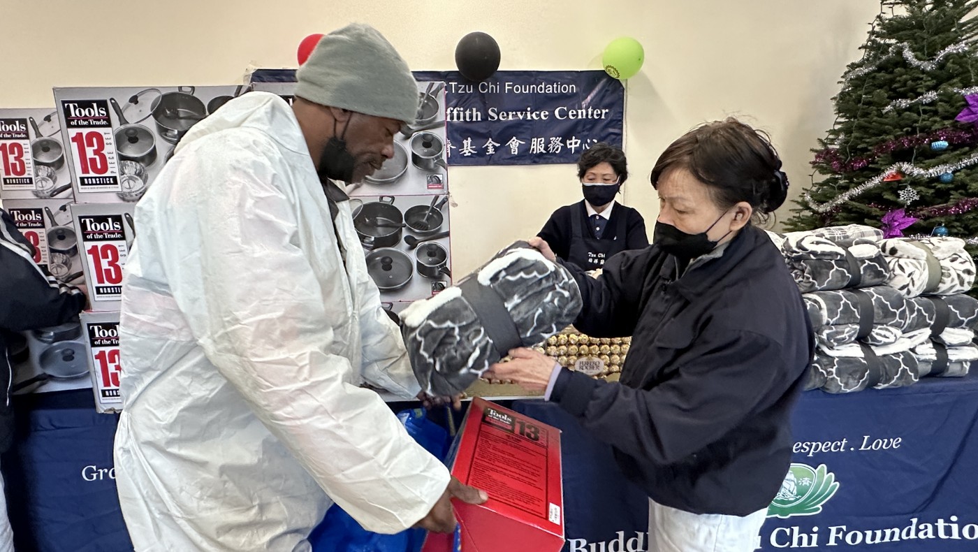 Tzu Chi volunteer giving cooking utensils, blankets, chocolates, toys, and other supplies to the community residents