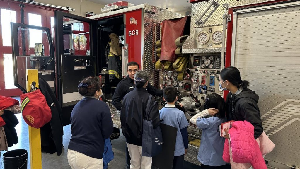 Fire fighter explaining fire fighting equipments to Tzu Chi USA Sacramento Jing Si Aphorism Children Class students and their parents
