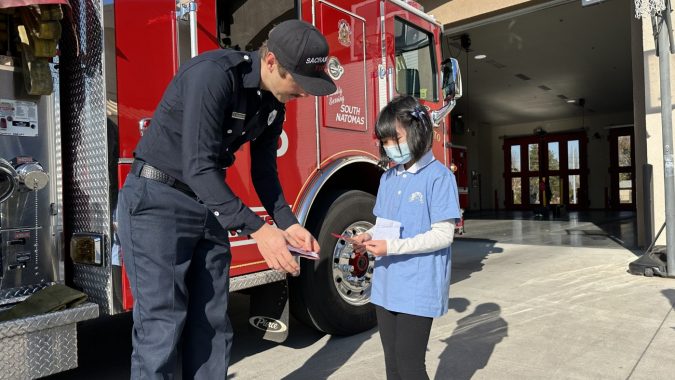 Tzu Chi USA Sacramento Jing Si Aphorism Children Class student giving thank you card to the fire fighter
