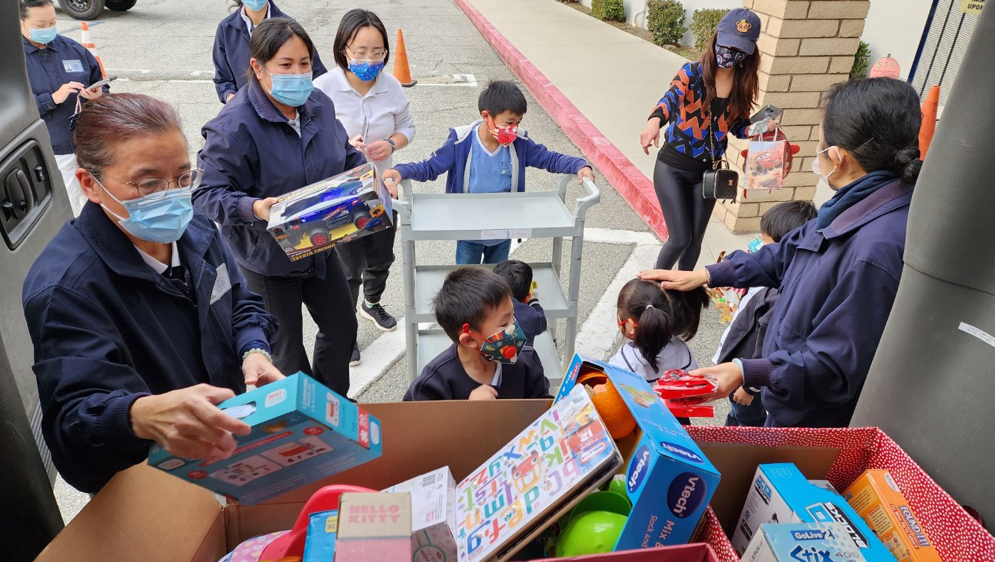 Tzu Chi volunteers and students putting donation toys into the truck
