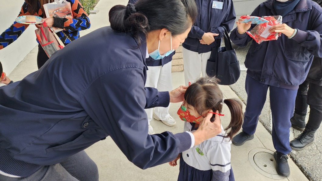 Tzu Chi USA volunteer putting face mask on student