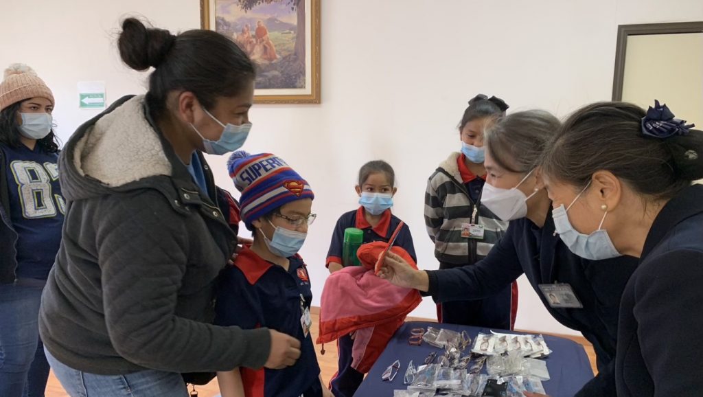 Tzu Chi volunteers and parents help the children try on their new glasses