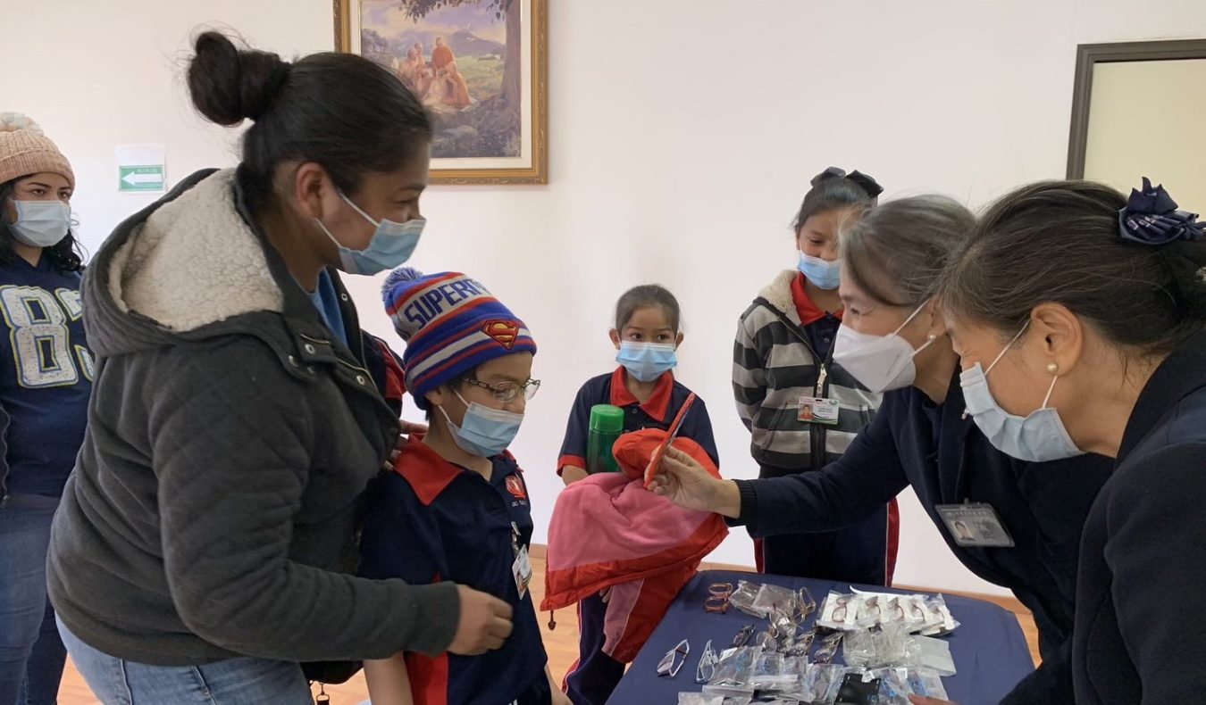 Tzu Chi volunteers and parents help the children try on their new glasses