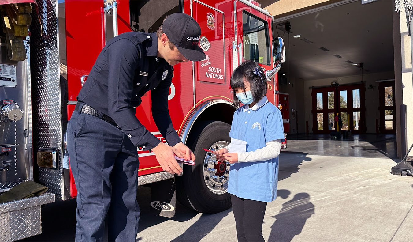 Tzu Chi Sacramento Youth class student present the thank you cards they made for the firefighter