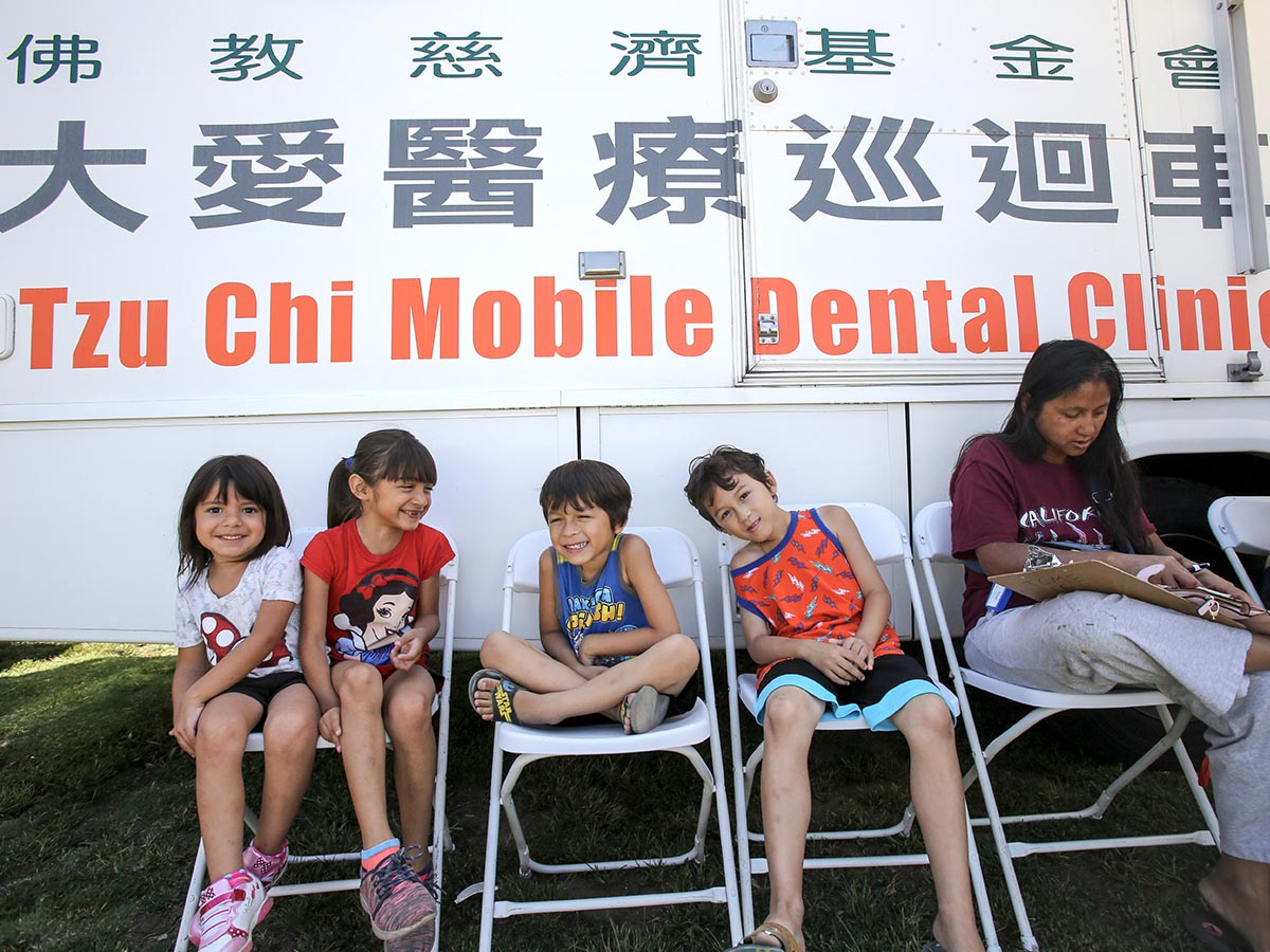 2017年牙科医疗车在南加州义诊，孩子露出笑脸，坐在医疗车前等候看诊。摄影／ Ringo Chiu