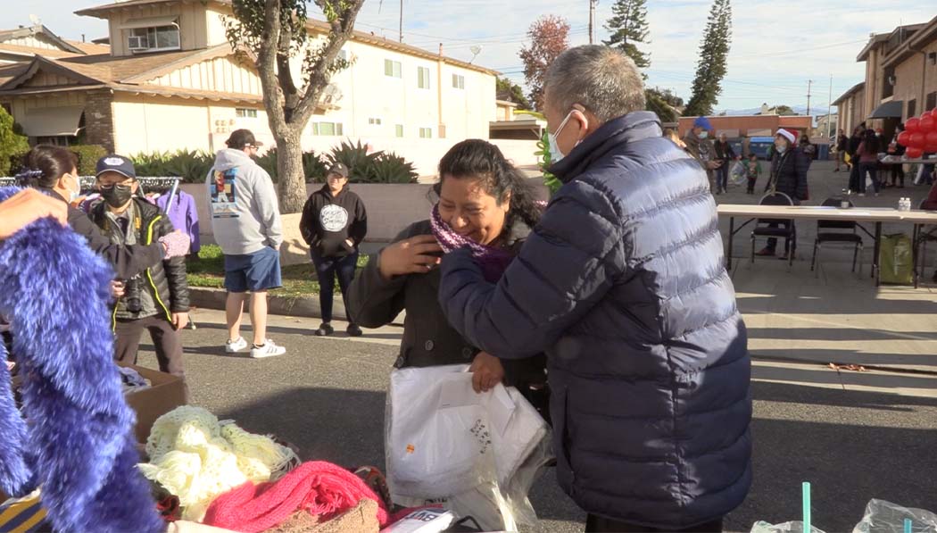慈濟志工熱情地為前來挑選發放物資的居民帶上圍巾，溫暖又可愛。圖片來源／慈濟美國總會