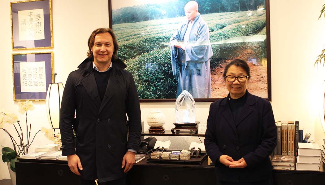 Alex Balint and Tzu Chi USA CEO Debra Boudreaux standing in front of Master Cheng Yen's photo