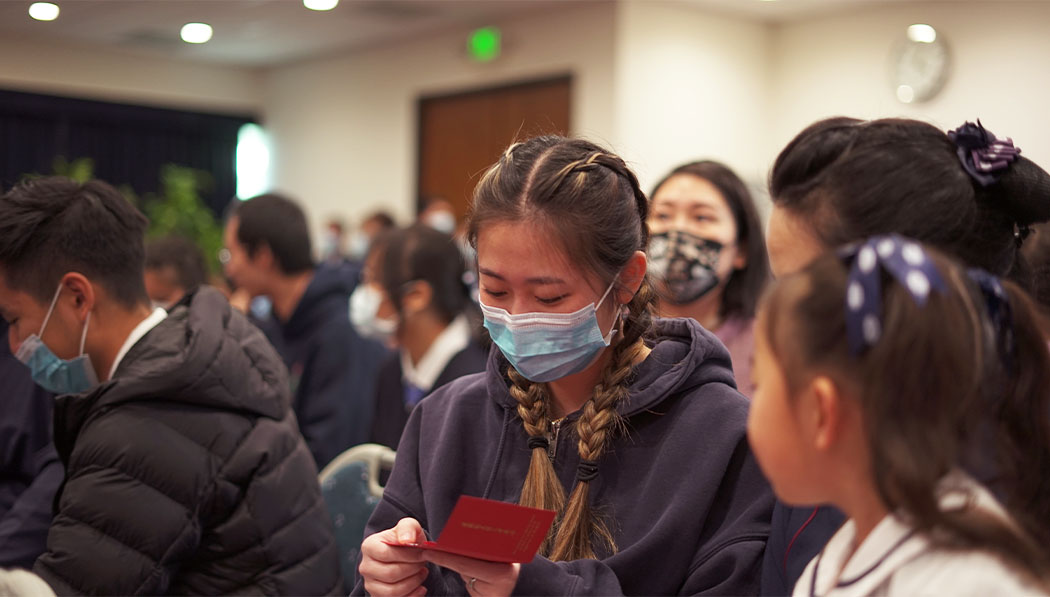 Tzu Chi youth volunteer looking into her blessing red envelope