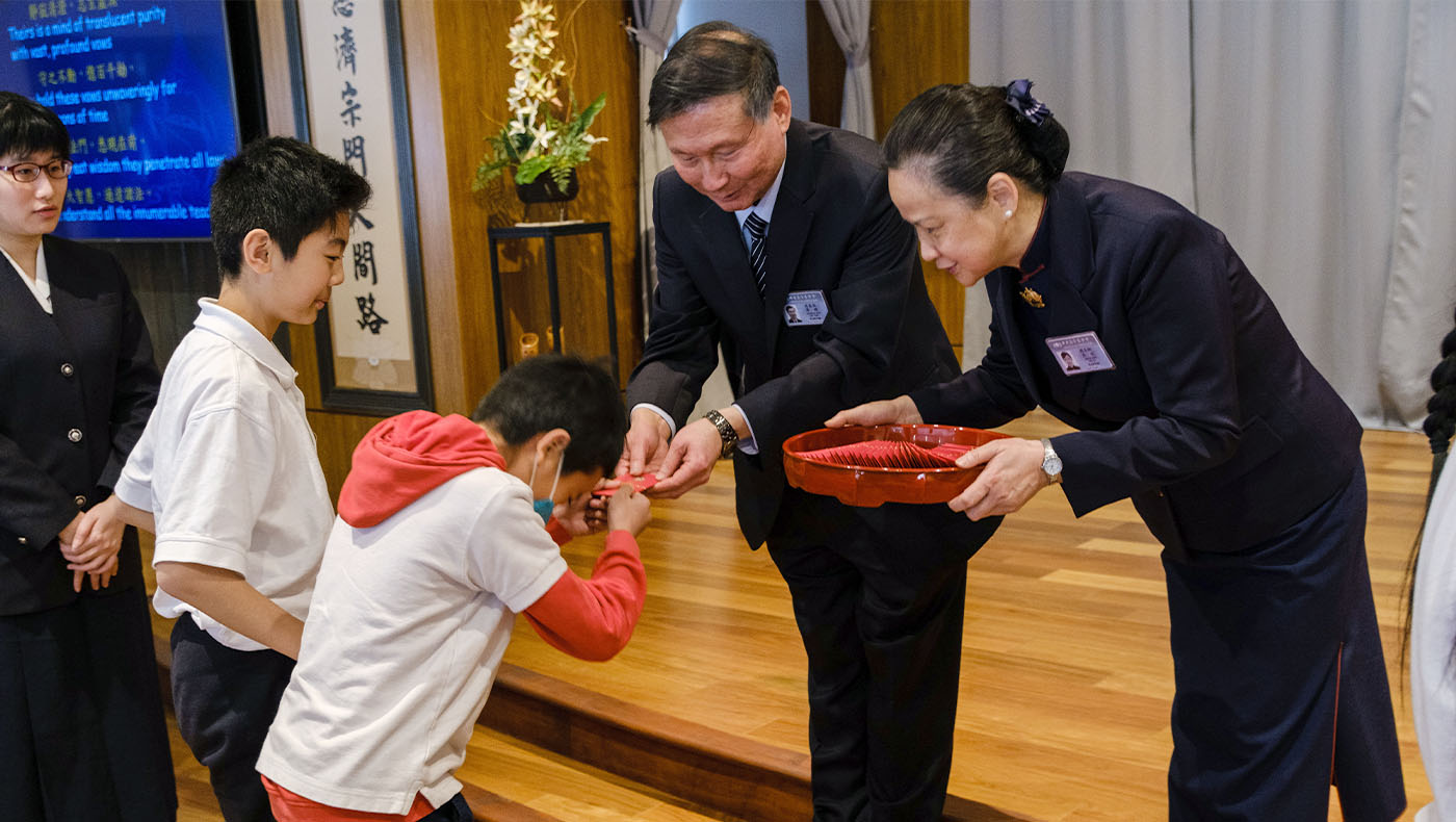 Children receiving Fuhui envelope from Master Cheng Yen