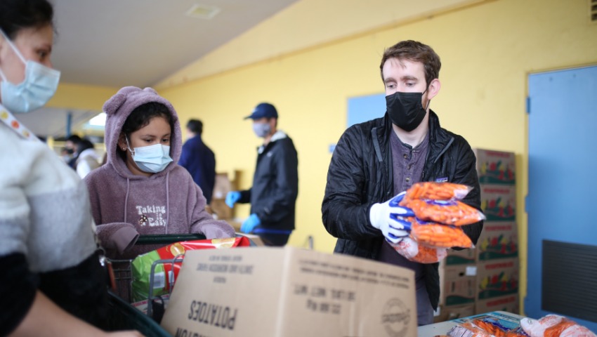 Young volunteer Noah distributes food to people in the community. Photo/ Steven Chiu