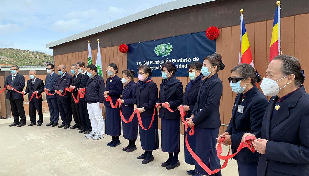 Tzu Chi volunteers standing in line and holding red ribbon