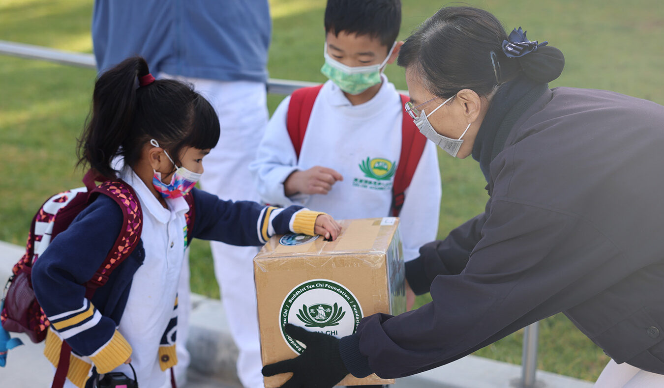 Tzu Chi Irvine Academy student putting money in donation box