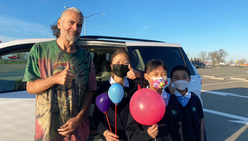 Mike Selinas, quien vive en su carro, agradece la ayuda recibida por Tzu Chi entregando globos a voluntarios.  Foto/Cai Xia Feng