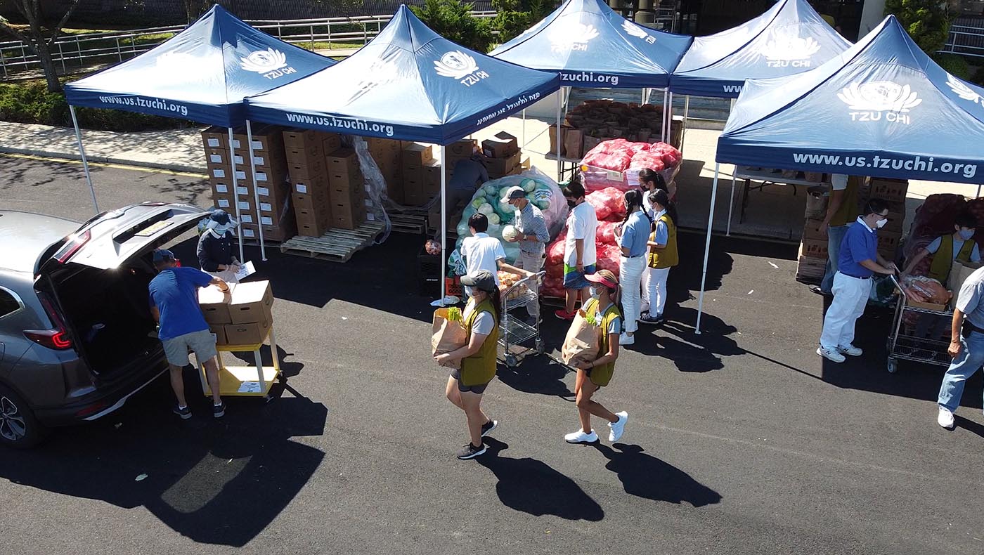 On August 5, 2022, Tzu Chi volunteers in New Jersey distribute food supplies under the scorching sun. Photo Wankang Wang