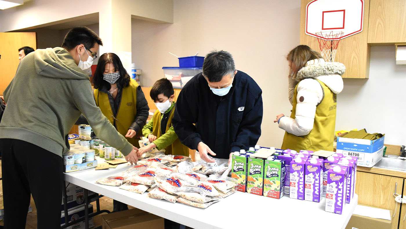 Tzu Chi volunteers work together to pack 3,000 pounds of vegetables and fruits into paper bags for subsequent distribution