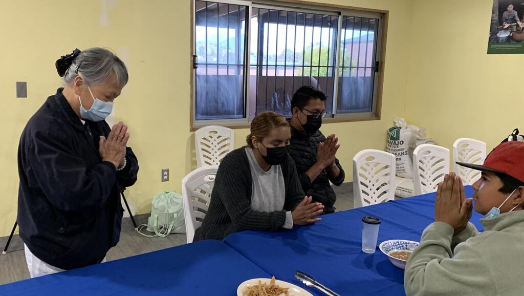 Before the meal, veteran volunteer Ah Mui Manguy (first from left) teaches everyone to pray with a grateful heart