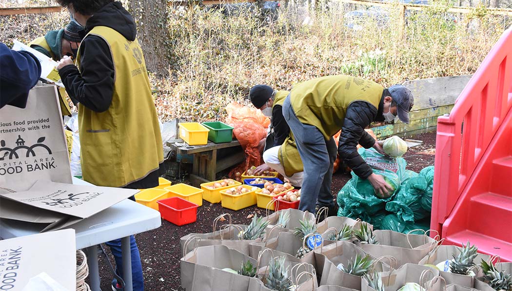 Durante el frío día de primavera, los voluntarios trabajan afuera para distribuir alimentos. Foto/Wendy Tsai
