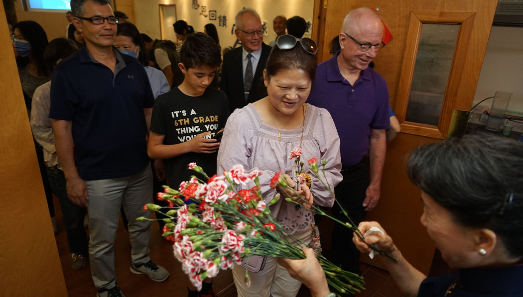 Tzu Chi volunteer offering flowers to visitor who is mother