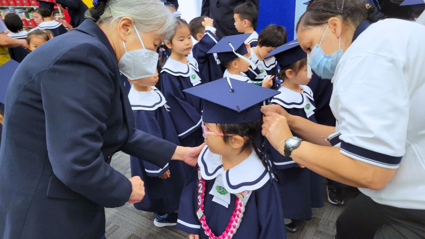 孩子在志工的幫助下穿戴好畢業生的衣帽。攝影／蔡怡暄