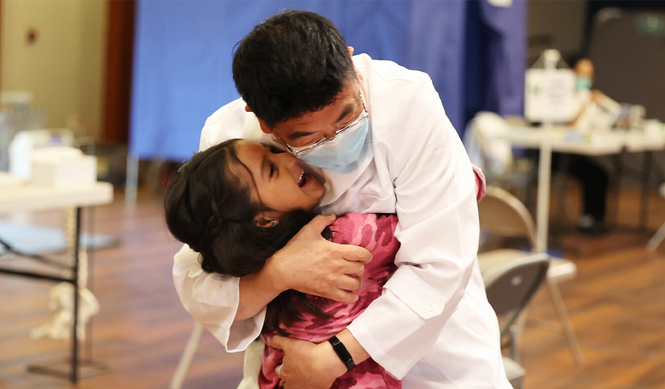 A little girl gratefully hugs the doctor who treated her brother.