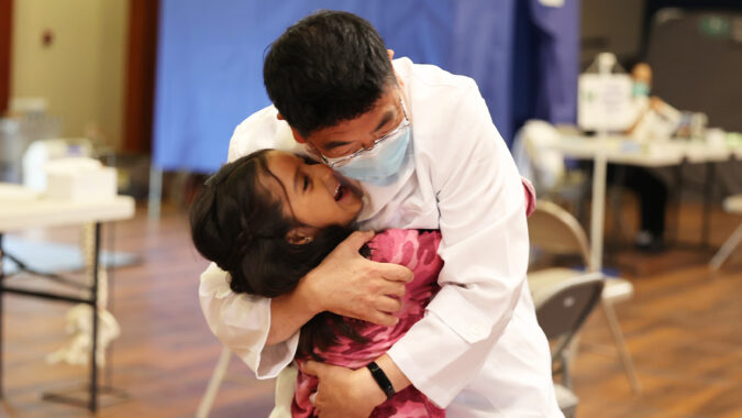 A little girl gratefully hugs the doctor who treated her brother.