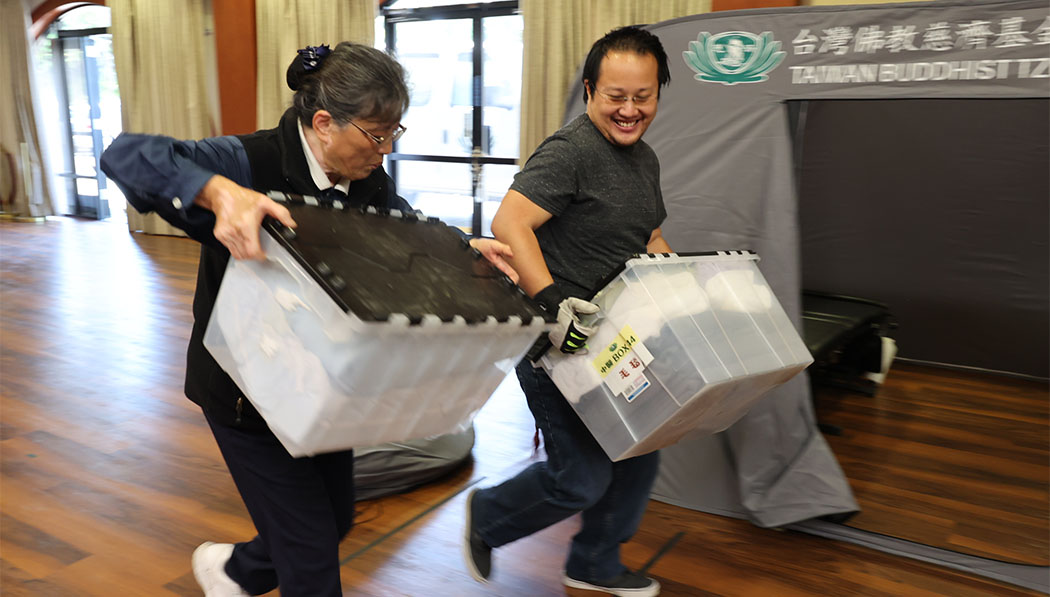 Tzu Chi volunteers carrying supplies boxes together