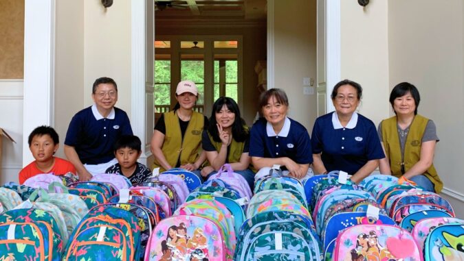 Volunteers take a photo with the school backpacks filled with stationery.