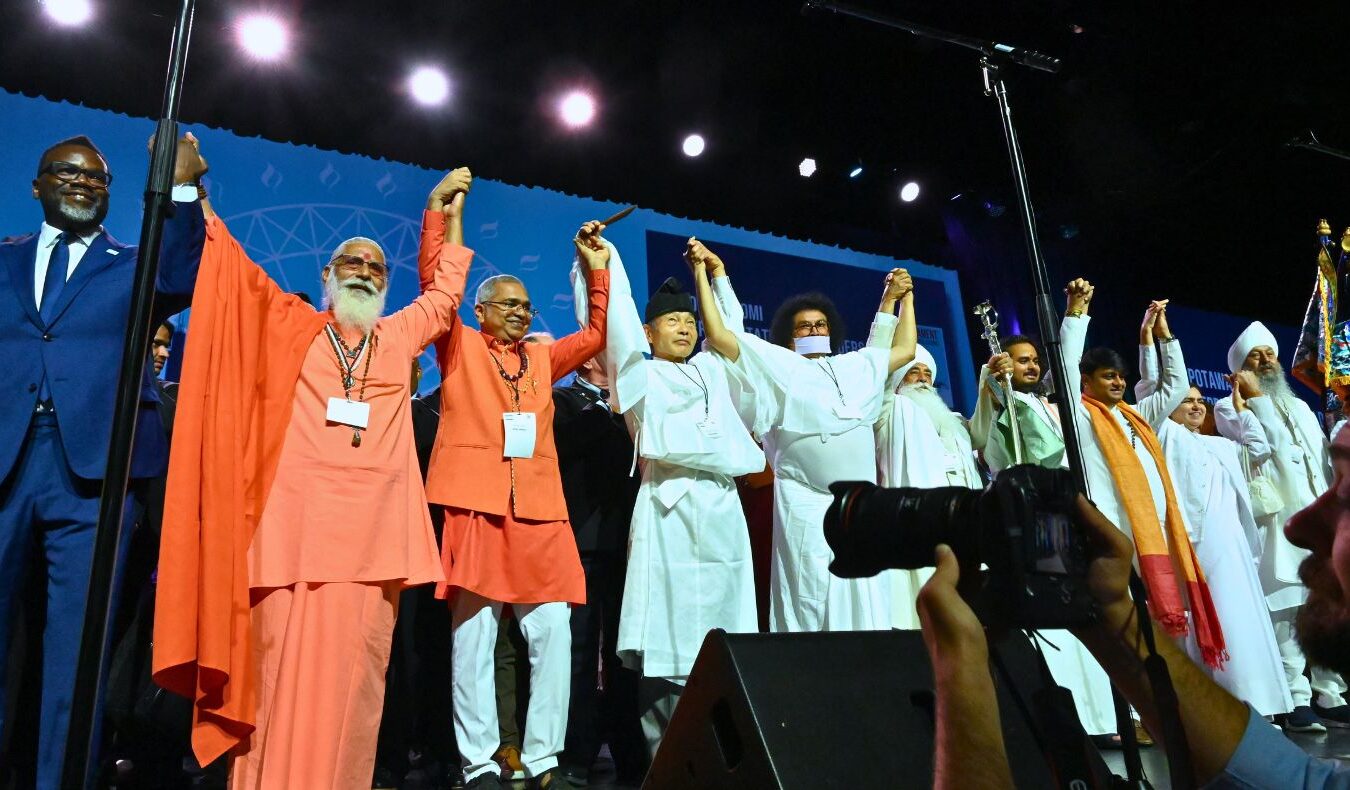 people from around the world join hands at the 2023 convening of the Parliament of the World’s Religions