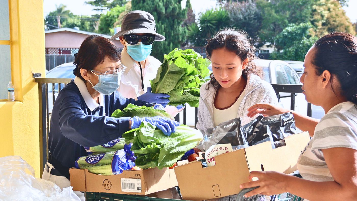 在食物銀行發放的區域，志工正在協助前來領取食物的居民將蔬果放入至手推車中。攝影／呂宛潔(Kitty Lu)