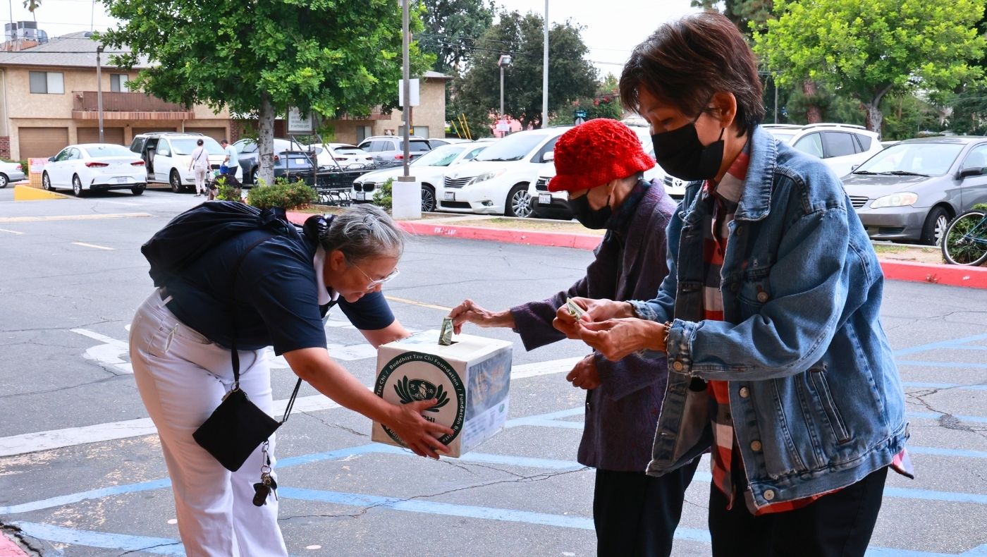 El 19 de agosto, los voluntarios de Tzu Chi recaudan donaciones frente a un supermercado. La gente  coloca dinero en la caja de recaudación. Foto/Shu Li Lo