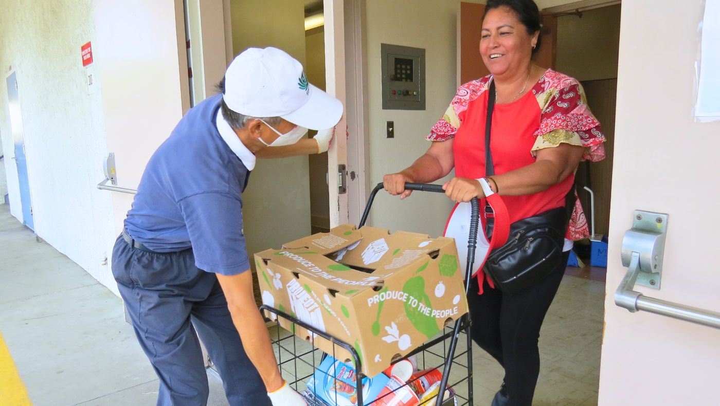 Voluntarios ayudan a los beneficiados a llegar los carritos de compra que pesan mucho con tantos alimentos. Foto/Feng Yuan Lin